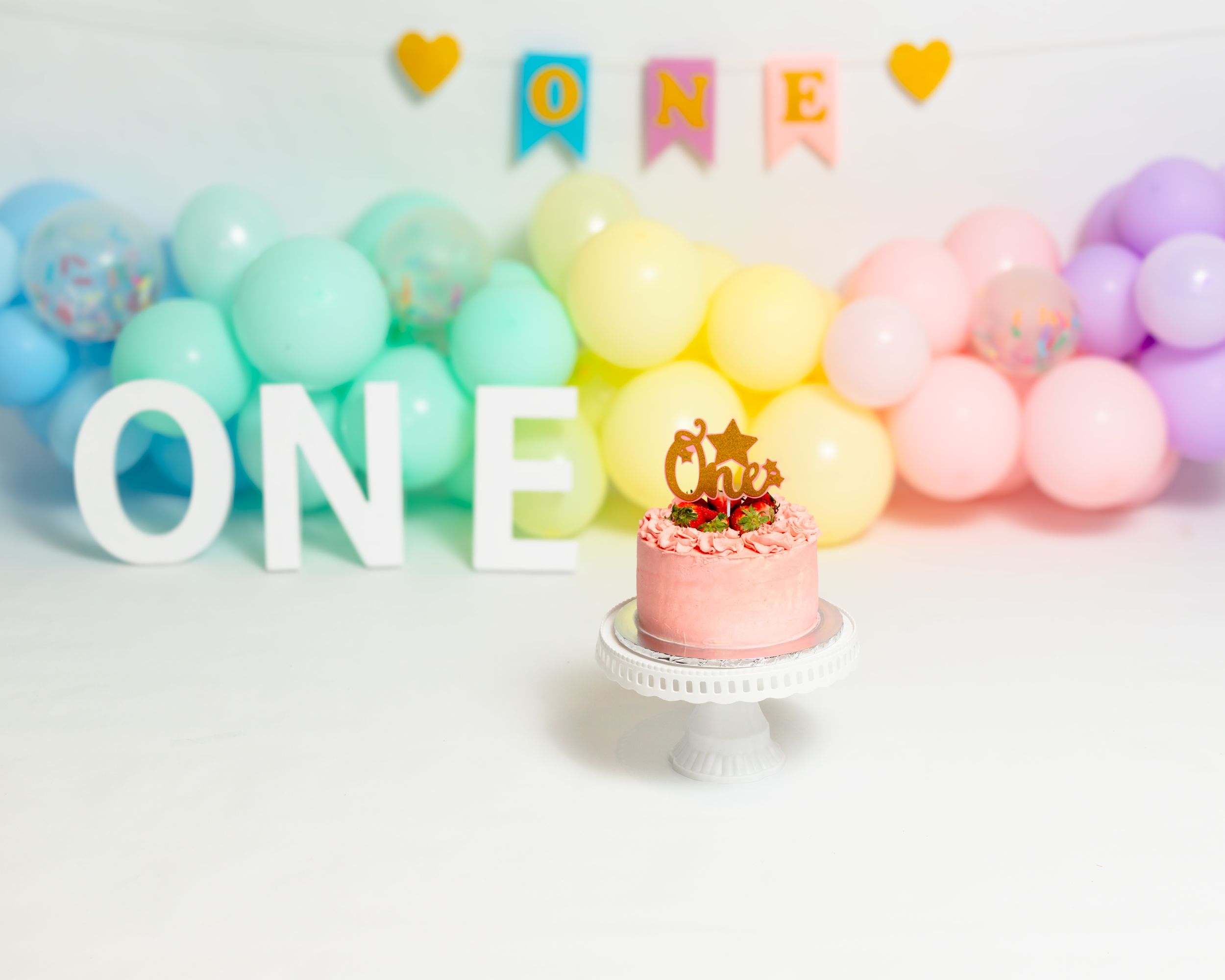 Pastel ONE balloons and a birthday cake ready for a cake smash