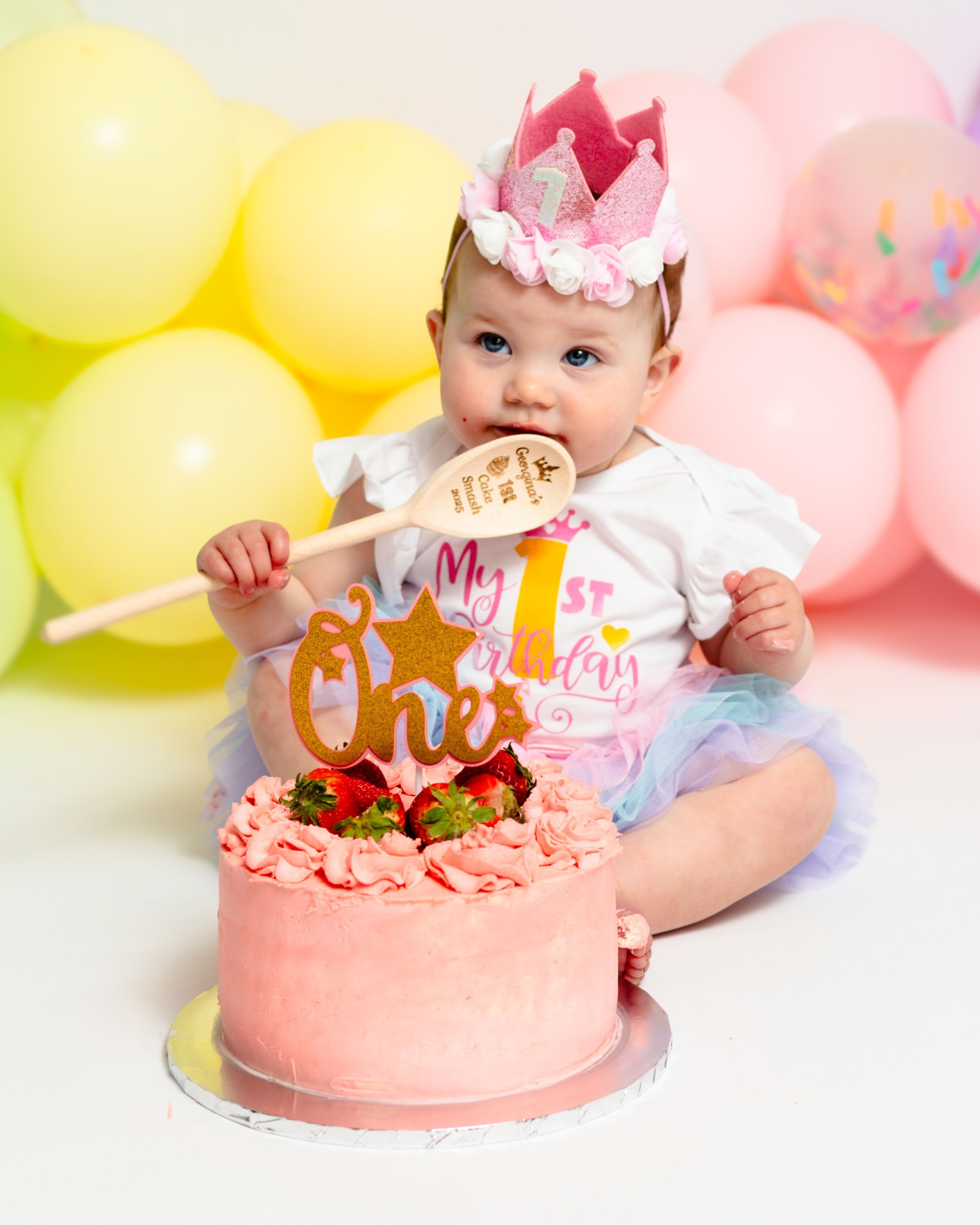 Baby girl in a crown at her pastel balloon cake smash